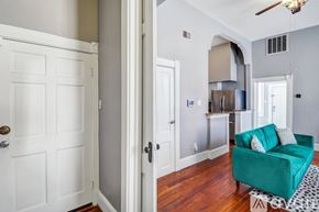 Savannah apartment for rent - A green couch with white pillows is in the middle of a room with a white door and a white wall.