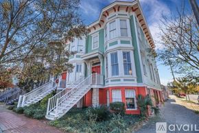 Savannah apartment for rent - A two-story house with a red and green exterior and white railings.