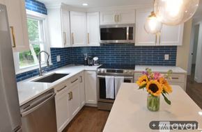 Bristol house for rent - A kitchen with white cabinets and a blue backsplash.