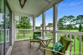 Myrtle Beach condo for rent - A patio with a table and chairs overlooking a grassy area.