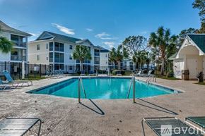 Myrtle Beach condo for rent - A pool surrounded by chairs and apartment buildings.