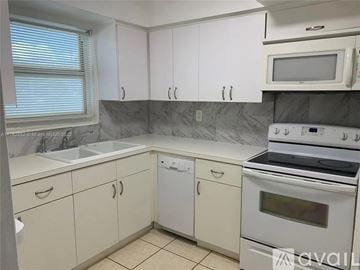 North Miami apartment for rent - A kitchen with white cabinets and a marble backsplash.