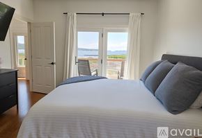 Onekama house for rent - A bedroom with a large bed and a view of the water.