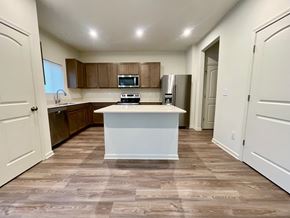 Louisville house for rent - A kitchen with a white island in the middle of a room with brown tiles.