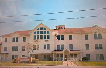 Hooverville apartment for rent - A white building with a red roof and an American flag on top.