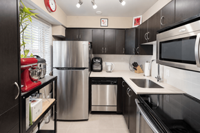 Vancouver apartment for rent - A modern kitchen with a stainless steel refrigerator, microwave, and dishwasher.