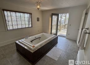 Dillard house for rent - A large bathtub is in a spacious bathroom with a window.