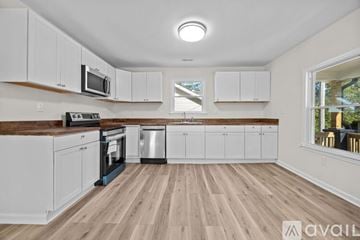 High Point house for rent - A kitchen with white cabinets and wooden floors.