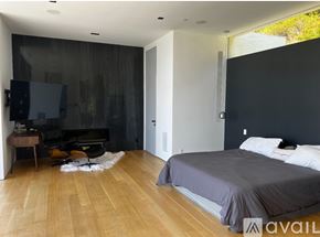 Los Angeles house for rent - A bedroom with a grey bed and wooden floors.