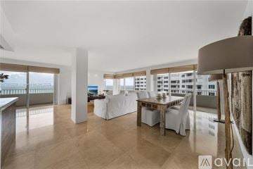 Key Biscayne condo for rent - A living room with a dining table and chairs, a couch, and a large window with a view of the city.