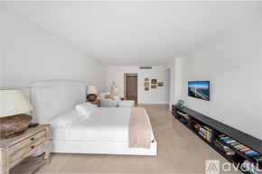 Key Biscayne condo for rent - A bedroom with a large bed and a TV on the wall.