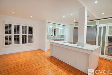 Key Biscayne house for rent - A kitchen with white cabinets and a wooden floor.