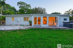 Key Biscayne house for rent - A house with a white exterior and a brown roof is surrounded by green grass.
