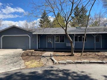 Post Falls house for rent - A house with a grey garage door and a tree in front.
