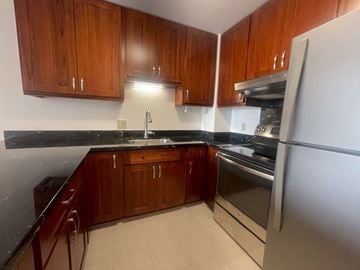 Honolulu apartment for rent - A kitchen with wooden cabinets and a black countertop.