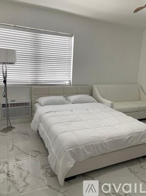 Miami Beach apartment for rent - A white bed with a white bedspread is in a room with a marble floor.