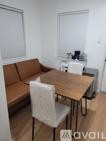 Miami Beach apartment for rent - A brown couch sits in a living room with a wooden table and white chairs.