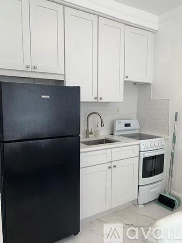 Miami Beach apartment for rent - A black refrigerator is in a kitchen with white cabinets.