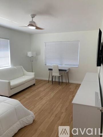 Miami Beach apartment for rent - A living room with a white couch, a small table with two chairs, and a television.