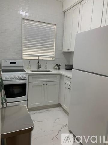 Miami Beach apartment for rent - A kitchen with white cabinets and a white fridge.
