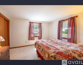Lisbon townhouse for rent - A bedroom with a bed, nightstand, and window with curtains.
