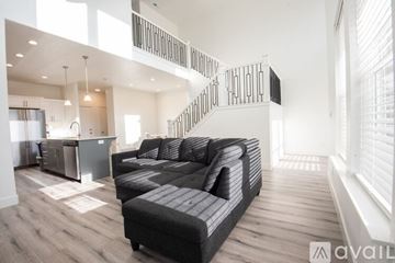 Lehi apartment for rent - A modern living room with a black sofa and a kitchen area in the background.
