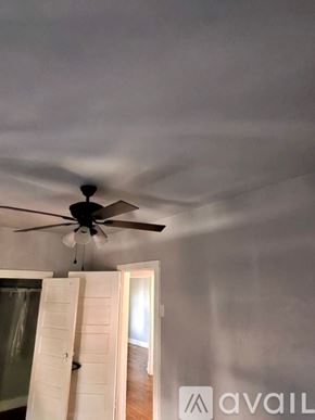 Chicago apartment for rent - A room with a ceiling fan and a window with a curtain.