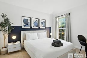 Frisco house for rent - A bedroom with a white bed, a white nightstand with a lamp, a plant, and three framed pictures on the wall.
