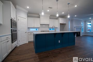 Cave Springs house for rent - A kitchen with white cabinets and a blue island.