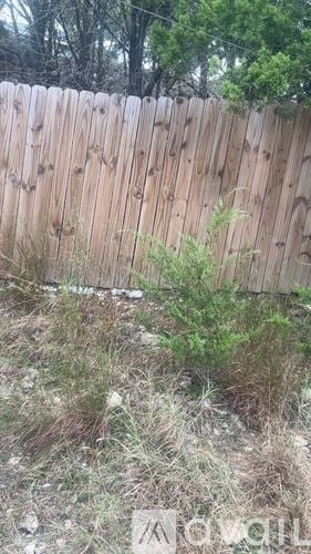 Spring Branch house for rent - A wooden fence with grass and weeds in front of it.