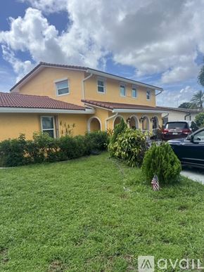 Coconut Creek house for rent - A kitchen with a black refrigerator, a microwave, a wooden cabinet, and a painting on the wall.