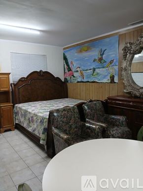 Coconut Creek house for rent - A bedroom with a bed, chair, and a painting on the wall.