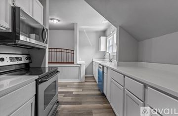 Butler apartment for rent - A modern kitchen with white cabinets and a wooden floor.