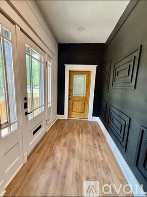 Greenville condo for rent - A hallway with a wooden floor, white walls, and a wooden door.