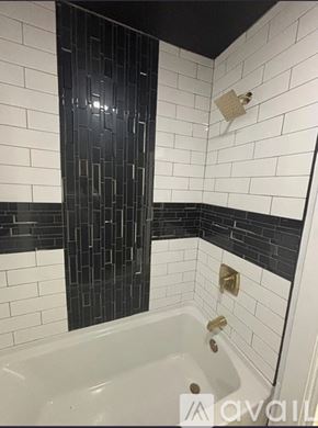 Greenville condo for rent - A bathroom with a white tub and black and white tiles.