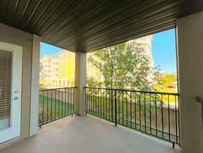 St. Albert apartment for rent - A balcony with a metal railing and a view of a green lawn and buildings.