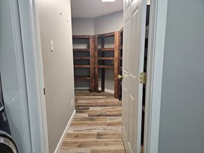Edmonton apartment for rent - A hallway with a washer and dryer on the left and a wooden door on the right.