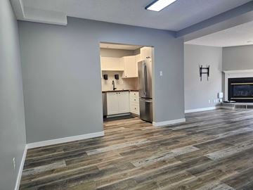 Edmonton apartment for rent - A kitchen with a refrigerator, oven, and cabinets is visible through an open doorway.