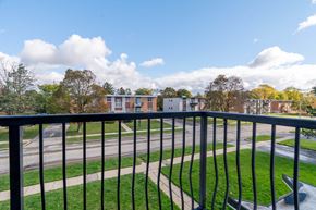 Waterloo apartment for rent - A view from a balcony overlooking a grassy area and a road with houses in the distance.