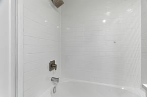 Kitchener apartment for rent - A white tiled shower with a shower head and faucet.