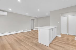 Waterloo apartment for rent - A white kitchen island sits in the middle of a room with wooden floors and white walls.