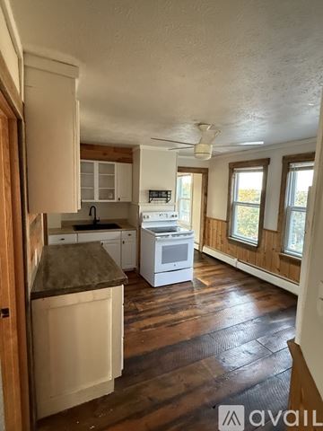 Biddeford apartment for rent - A kitchen with wooden cabinets and a white stove top oven.