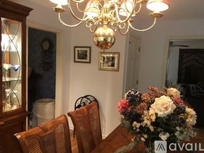 Woodbury house for rent - A dining room with a chandelier, two chairs, and a table with a vase of flowers.