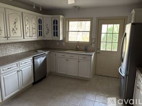 Woodbury house for rent - A kitchen with white cabinets and a black dishwasher.