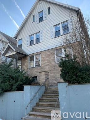 Hillside apartment for rent - A house with a staircase leading to the front door.