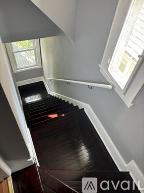 Hillside apartment for rent - A staircase with a wooden floor and white railings.