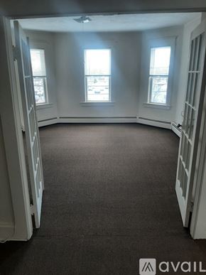 Lowell apartment for rent - A room with a carpeted floor and three windows.
