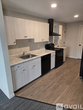 Lowell apartment for rent - A kitchen with white cabinets and a black stove top oven.