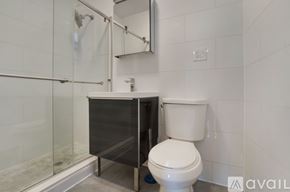New York apartment for rent - A white toilet sits next to a walk-in shower in a bathroom.