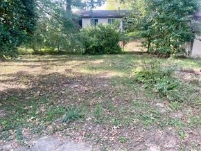 Jeffersonville house for rent - A backyard with a dirt area and a few trees.